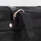 A black waxed canvas motorcycle pannier bag with attachment hoops
