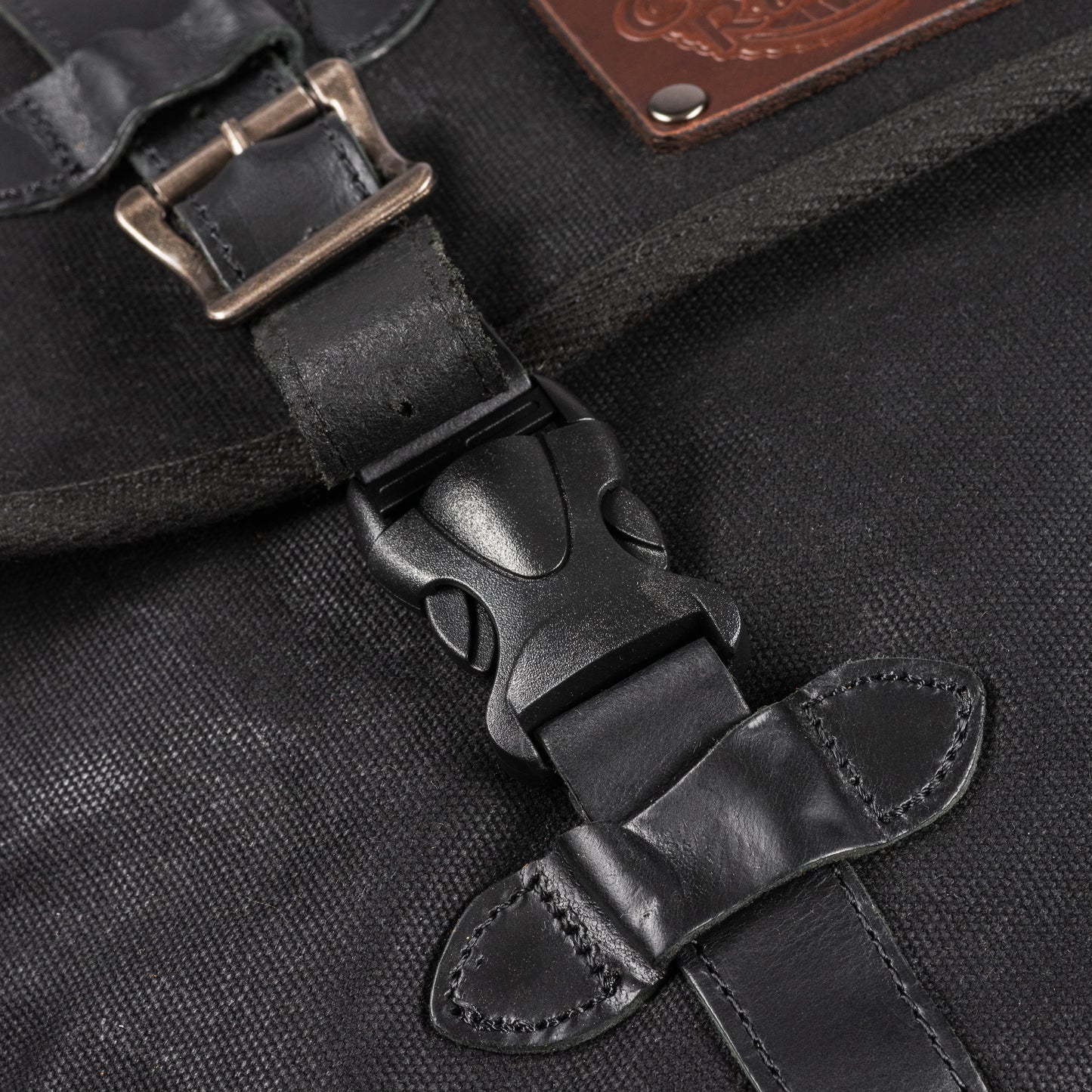 A black waxed canvas motorcycle pannier bag side release buckles