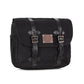 A black waxed canvas motorcycle pannier bag with side release buckles and a detachable shoulder strap.