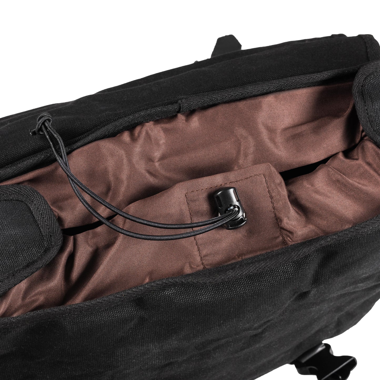 The interior of a black waxed canvas motorcycle pannier bag with side release buckles and a detachable shoulder strap.